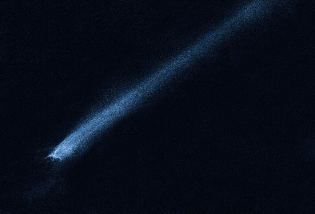 The Hubble Space Telescope being deployed from a space shuttle into orbit, with solar panels extended against the black backdrop of space and the sun shining brightly behind the observatory.